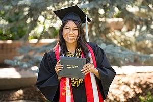 Smiling Graduate with her diploma on graduation day